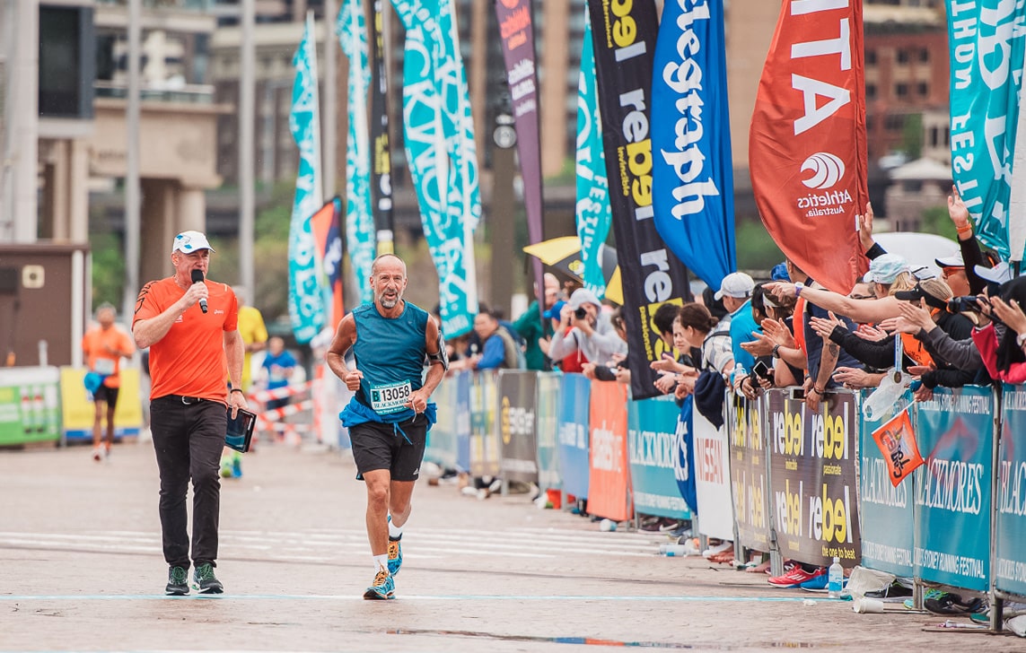 a runner is crossing the finish line at Sydney running festival annual event