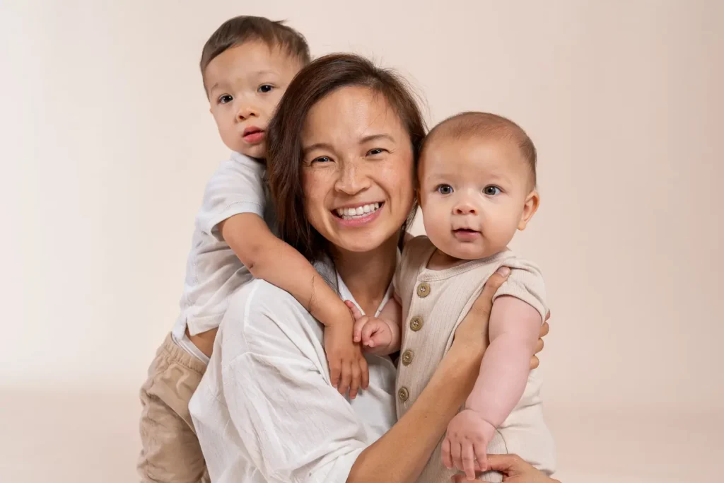 Mother with two children smiling in a studio portrait for Karitane annual report photography