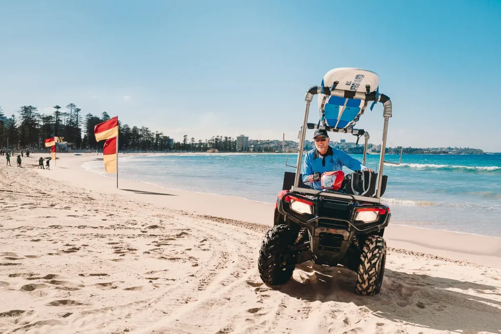 Northern Beaches surf lifesaver driving along beach on patrol