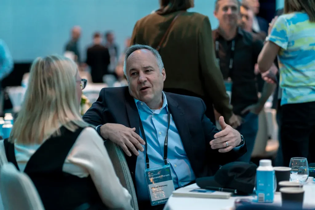 Attendees speaking near agenda signage at Guidewire Insurance Forum Sydney 2023