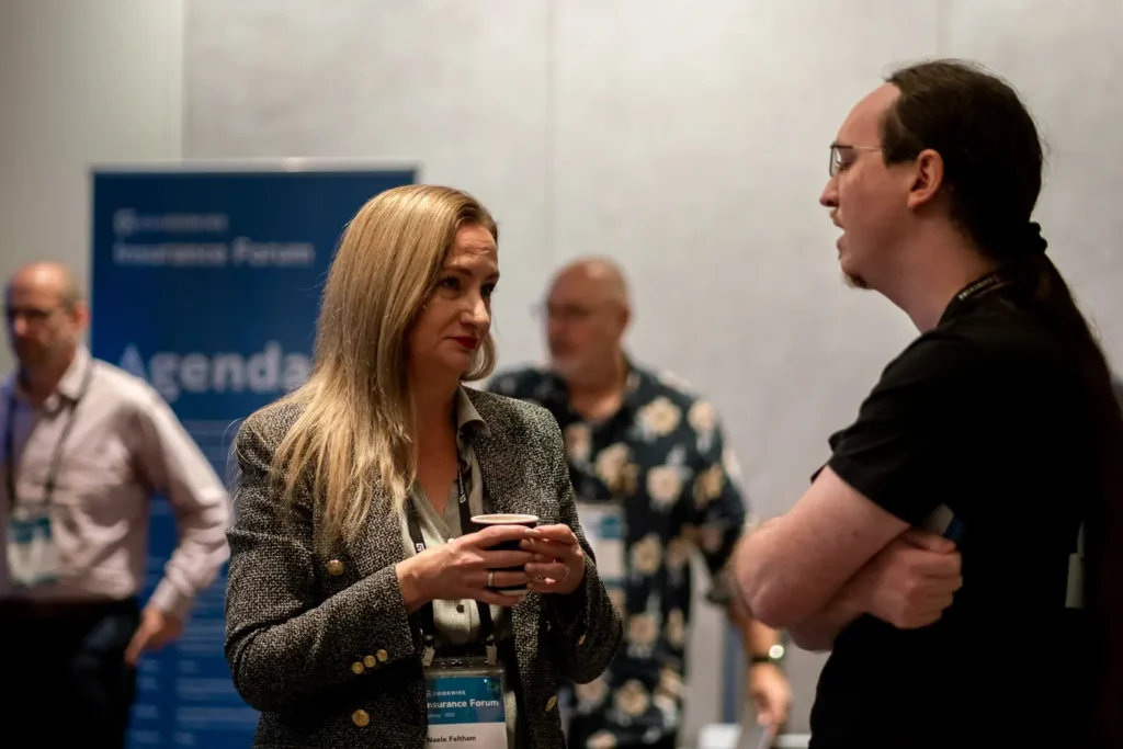 Attendees networking near event signage at Guidewire Insurance Forum Sydney 2023
