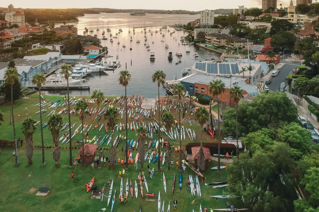 Aerial view of surf skis lined up on the grass beside Sydney Harbour before the race start