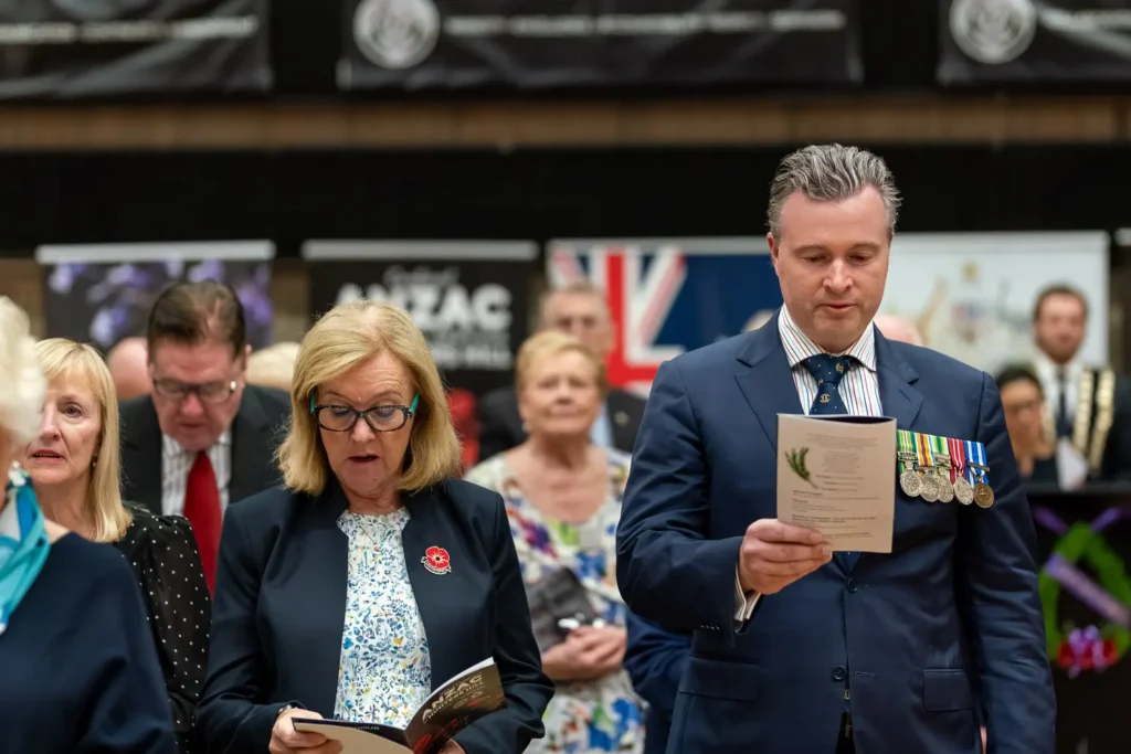 Attendees reading memorial service program during ANZAC ceremony in Hunters Hill