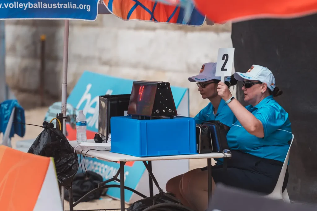 Volleyball officials managing the scoreboard and match points during a beach volleyball event