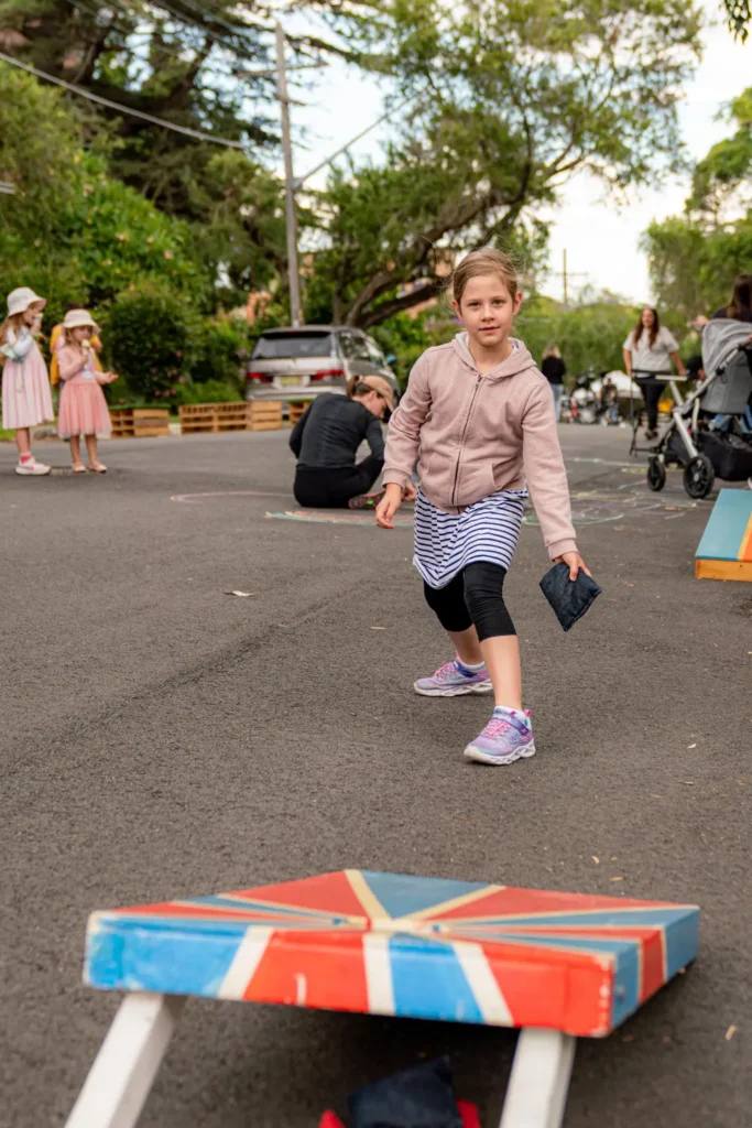 Child playing bean bag toss game during North Sydney Street Play event