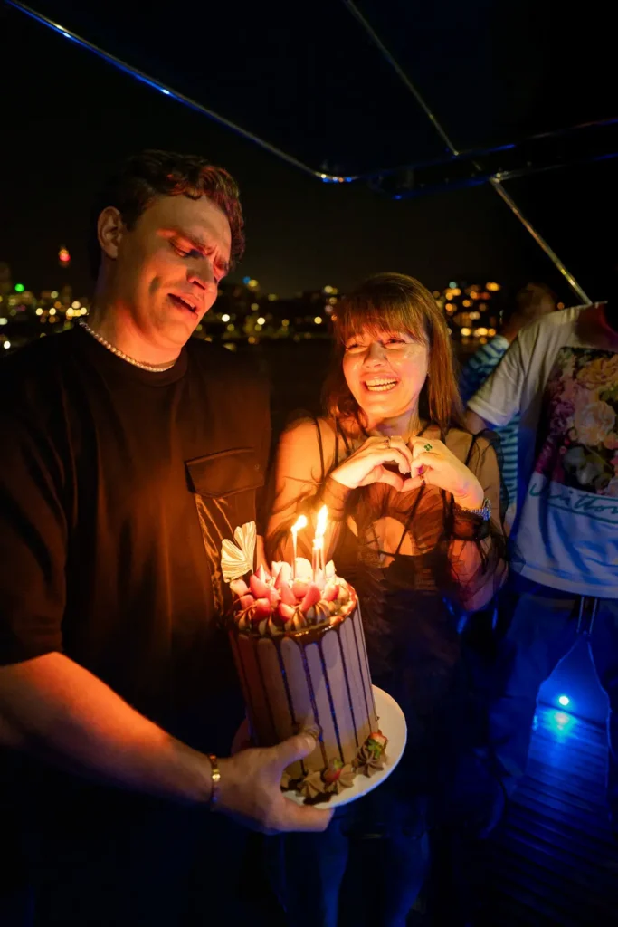 Guests celebrating with cake and candles during a night yacht party in Sydney Harbour
