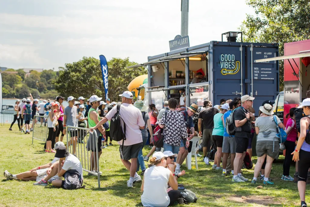 Participants lining up at food trucks during the Bridges Walk community event in Sydney