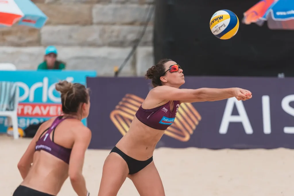 Canadian beach volleyball player diving forward for a defensive dig