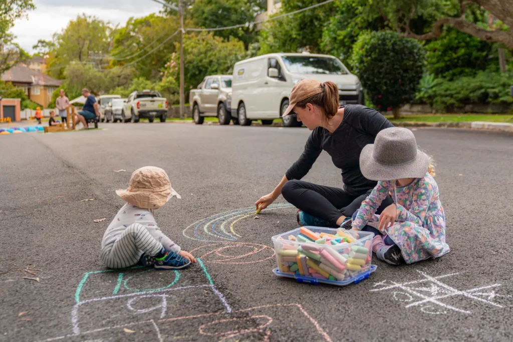 Family drawing colourful chalk art on the street during Wollstonecraft community event