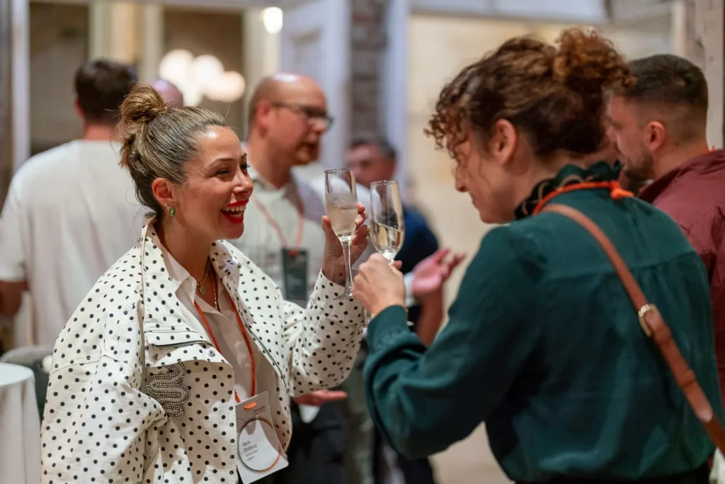 Two attendees toasting champagne glasses while chatting at a business networking reception