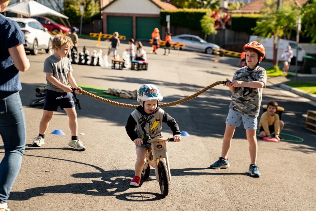 Children playing a balance bike tug game during a fun outdoor community activity