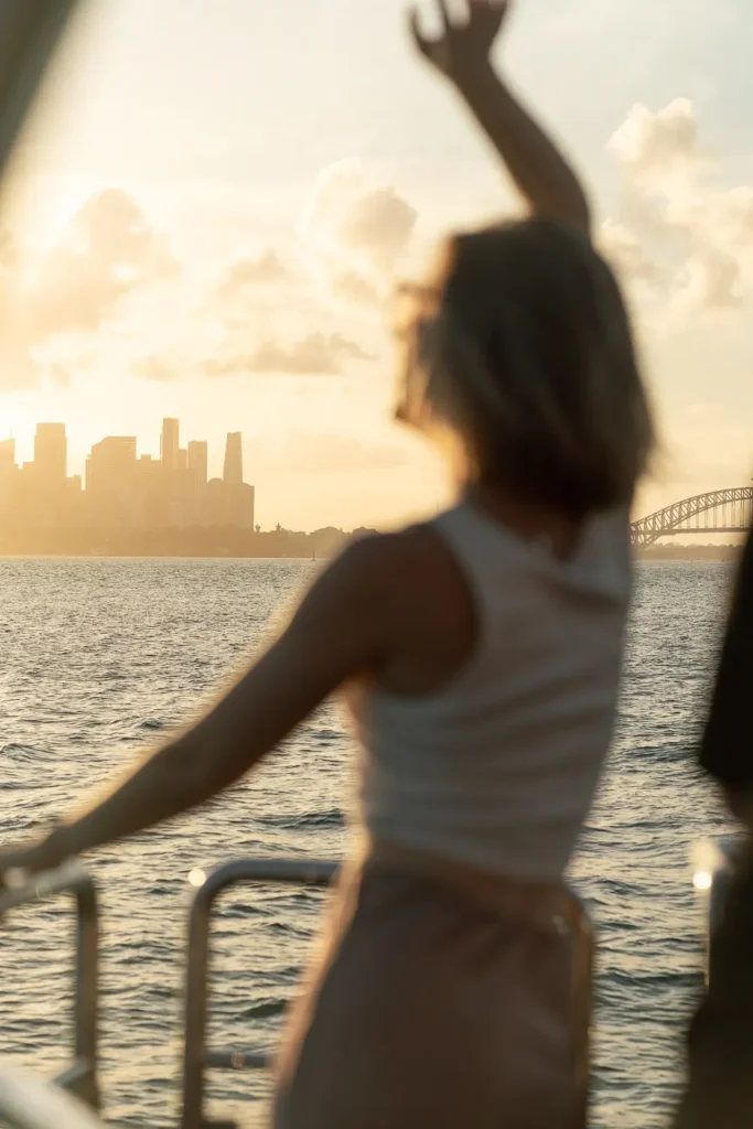 Soft focus portrait of a woman dancing on a yacht at sunset with Sydney skyline in the background