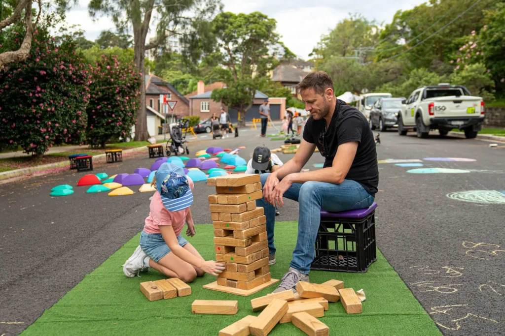 Father and child playing giant Jenga on a closed residential street during a family activity day