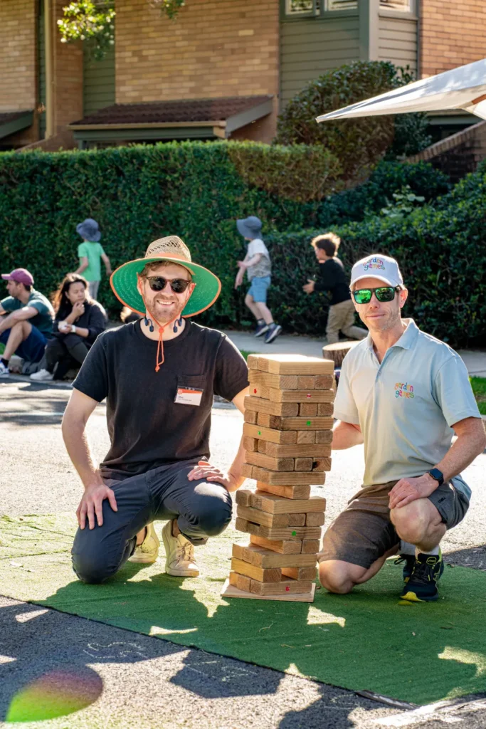 Community organisers posing beside a giant Jenga game during an outdoor neighbourhood festival