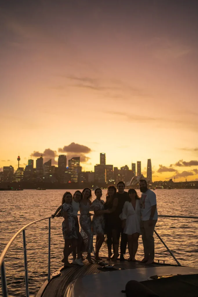 Friends posing together on a yacht at sunset with Sydney skyline in the background