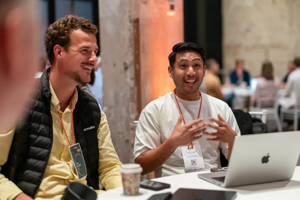 Attendees at a HubSpot Partner Summit networking roundtable discussing ideas around a table with laptops and coffee cups