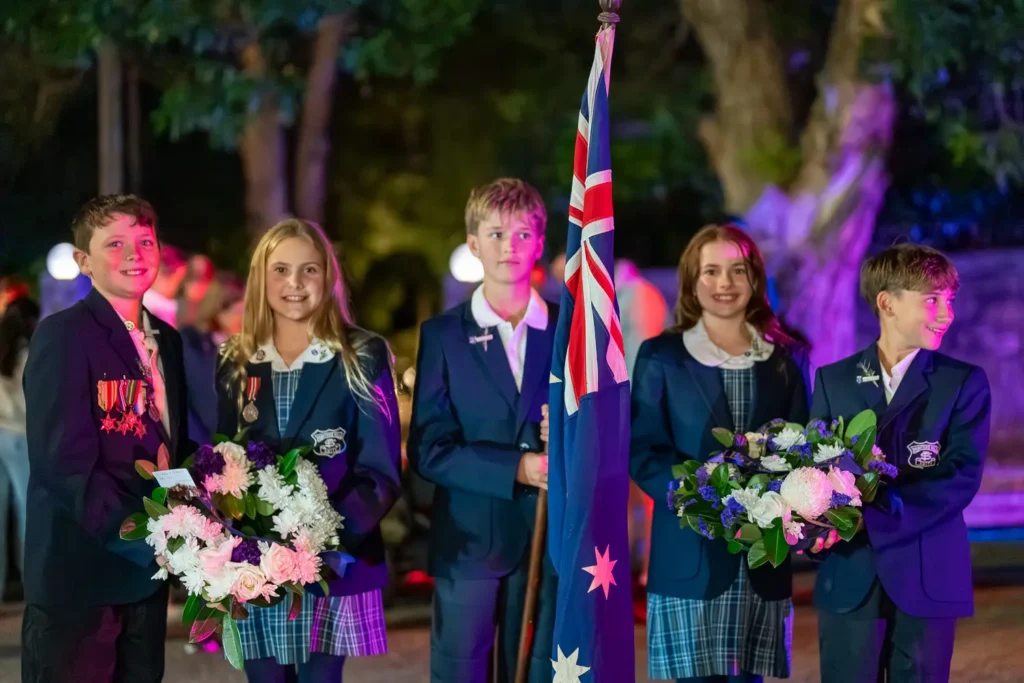 School students holding floral tributes during the Hunters Hill ANZAC service