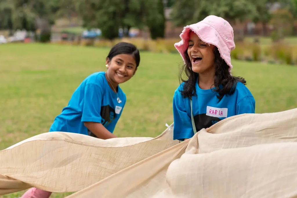 Children participating in a parachute teamwork game outdoors