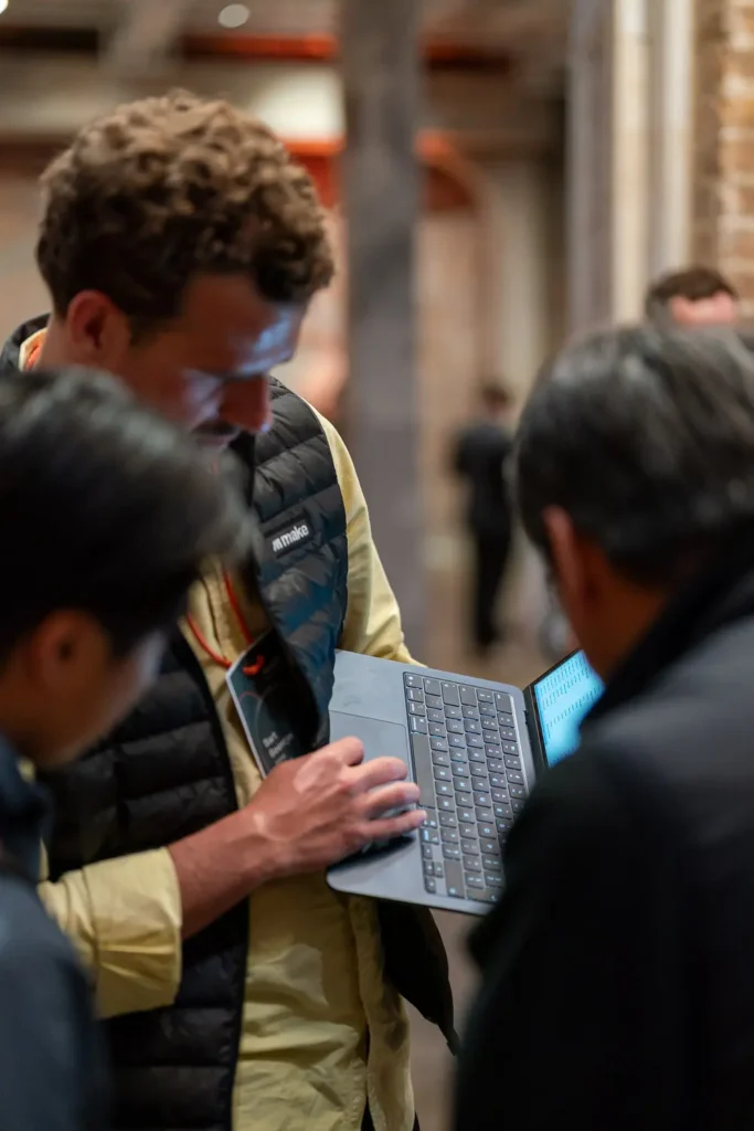 Event attendee demonstrating something on a laptop during a collaborative discussion at a tech networking event