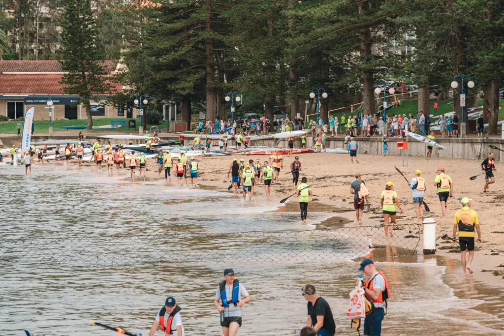 Athlete running barefoot with paddle during a beach transition in an ocean paddling race