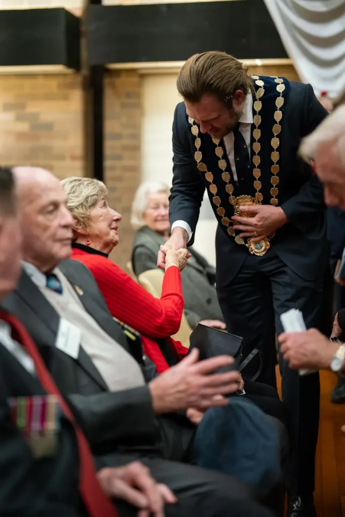 Mayor Zac Miles shaking hands with elderly attendee following ANZAC memorial ceremony
