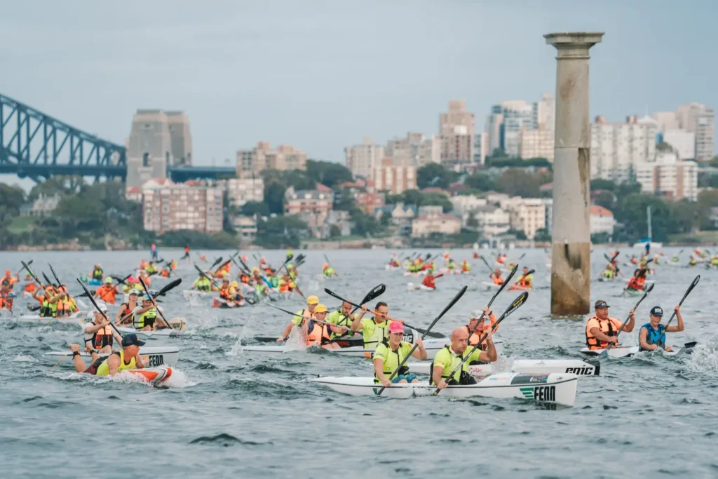 Competitors paddling through choppy water near a navigation marker on Sydney Harbour