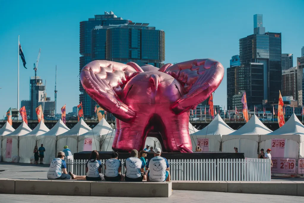 Large pink inflatable elephant sculpture beside festival tents at Darling Harbour