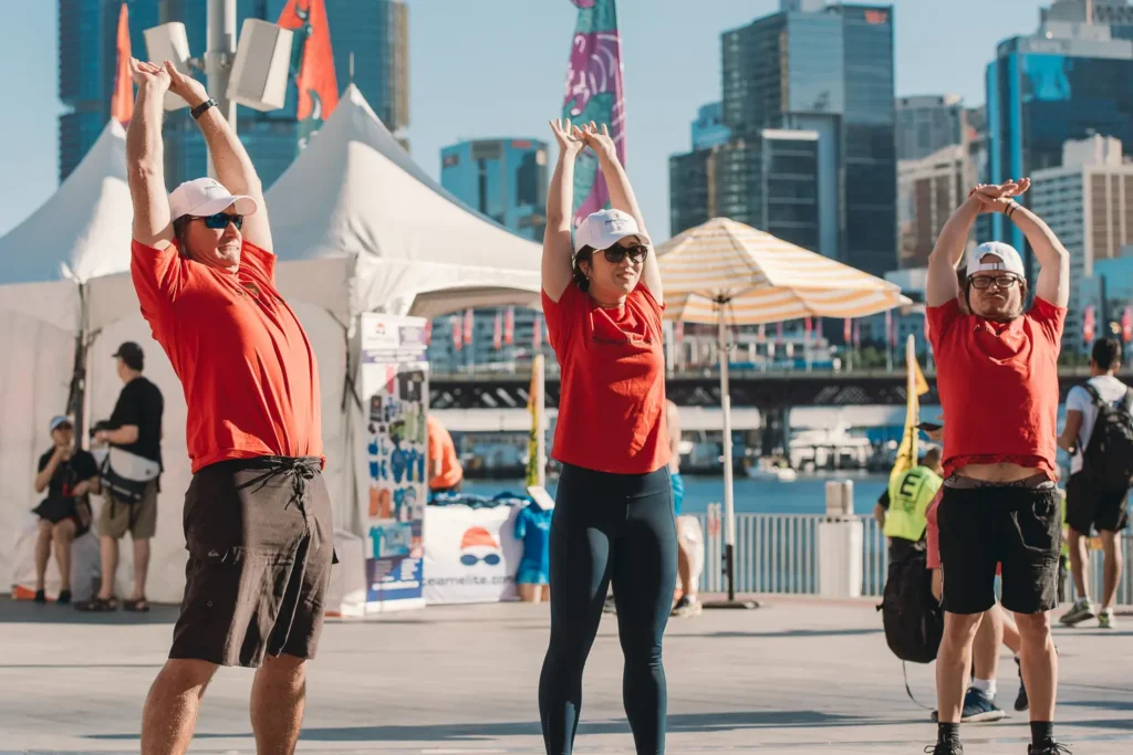 Participants stretching before dragon boat races at Sydney waterfront event
