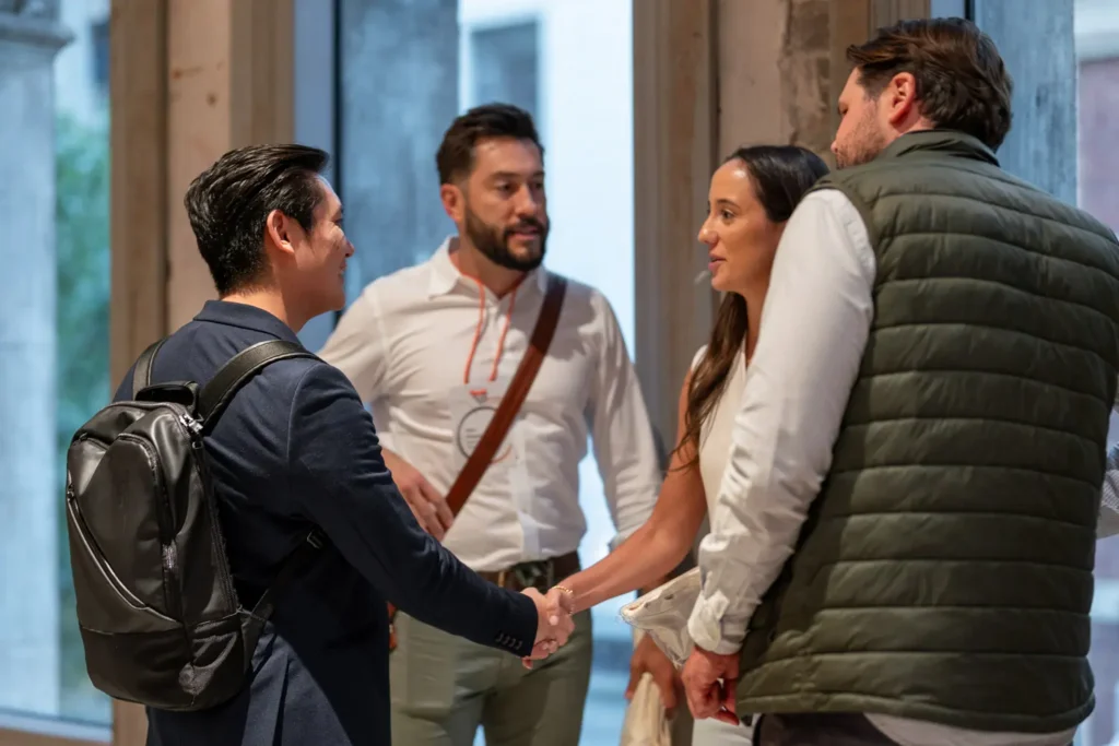 Two professionals shaking hands while introducing themselves at a business networking event