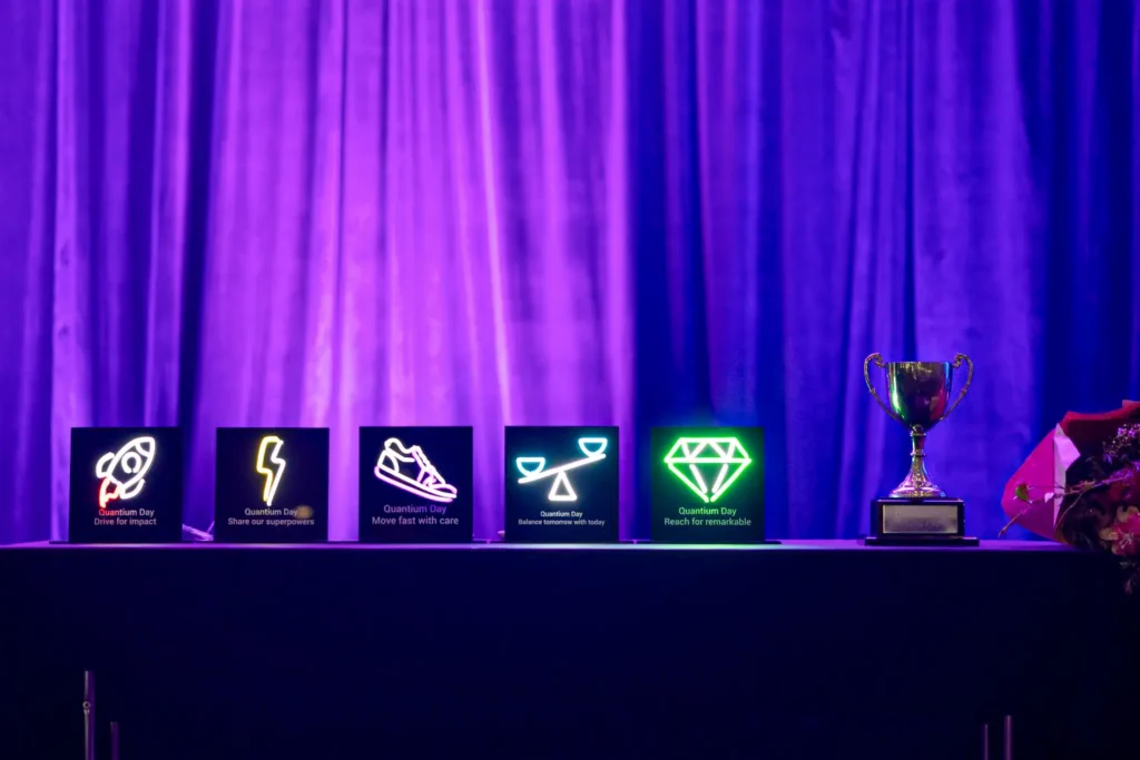 Quantum Day award trophies displayed on illuminated stage backdrop
