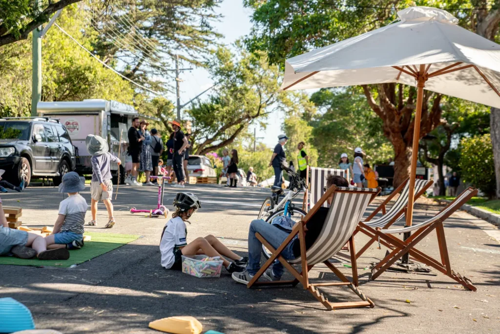 Families relaxing in deck chairs while children play in a car-free neighbourhood street
