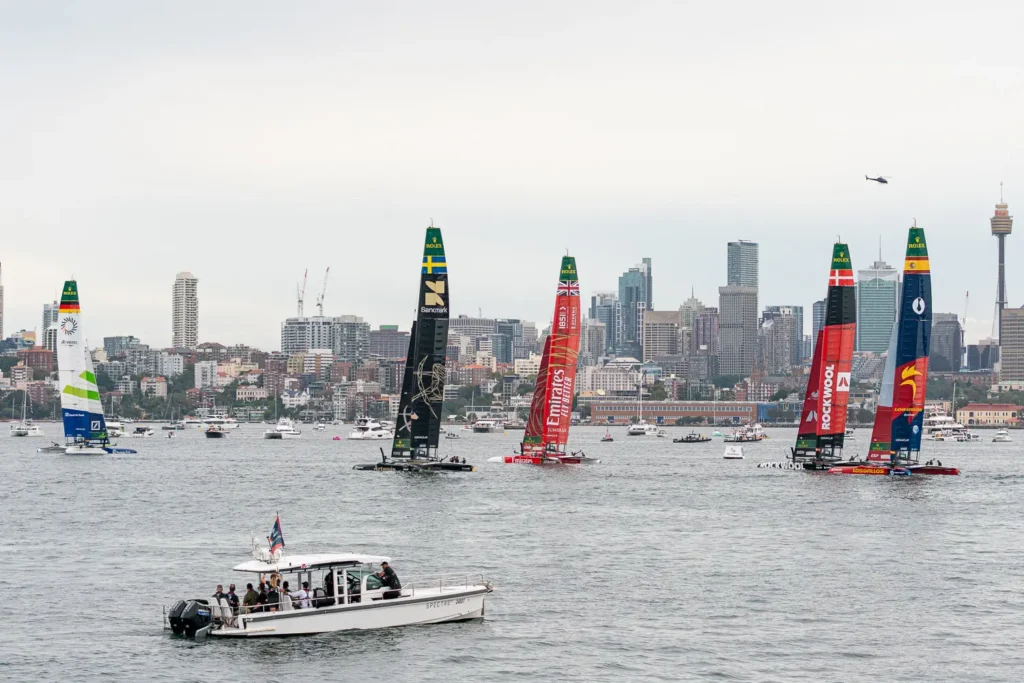 SailGP fleet racing across Sydney Harbour with the Sydney skyline visible in the background