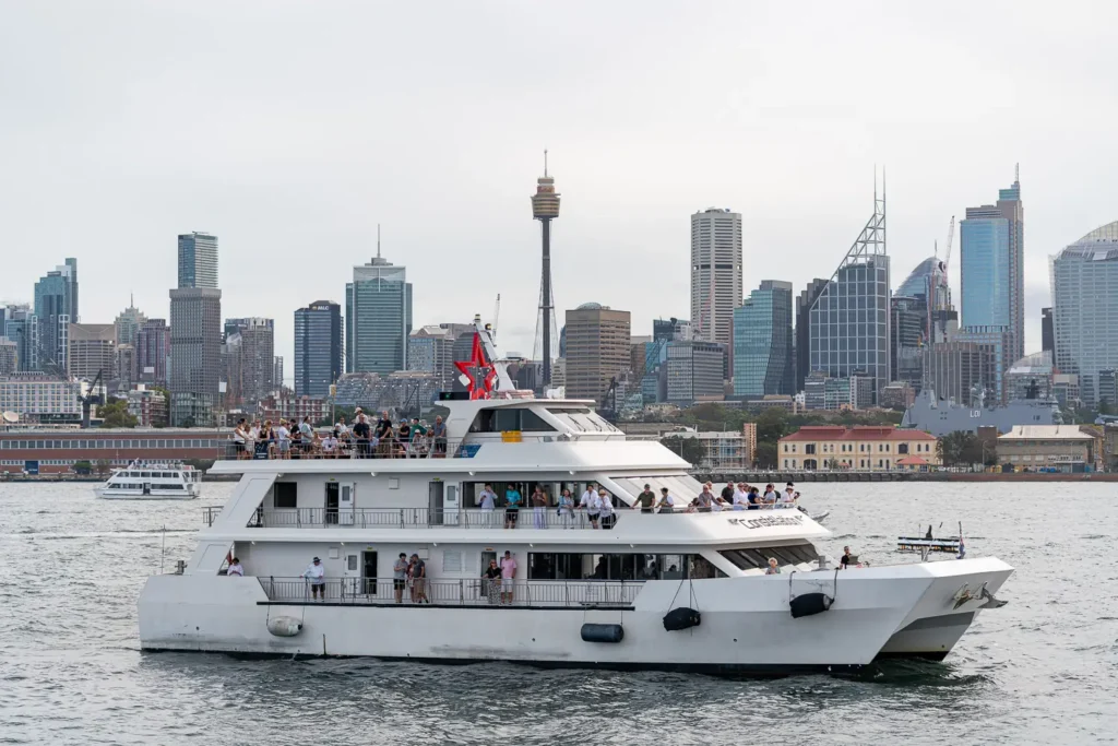 Spectator boat watching SailGP racing on Sydney Harbour with Sydney skyline behind