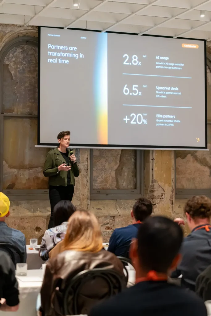 Sarah McDevitt presenting AI growth insights during a corporate partner summit conference