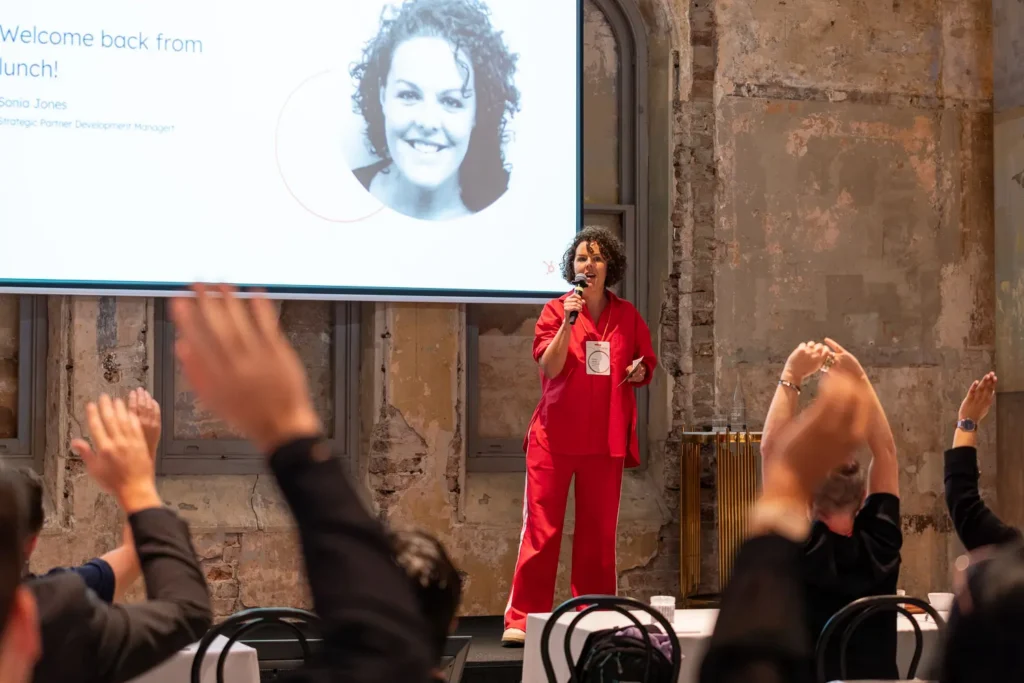 Sonia Jones speaking on stage during a corporate partner summit conference presentation with audience participation