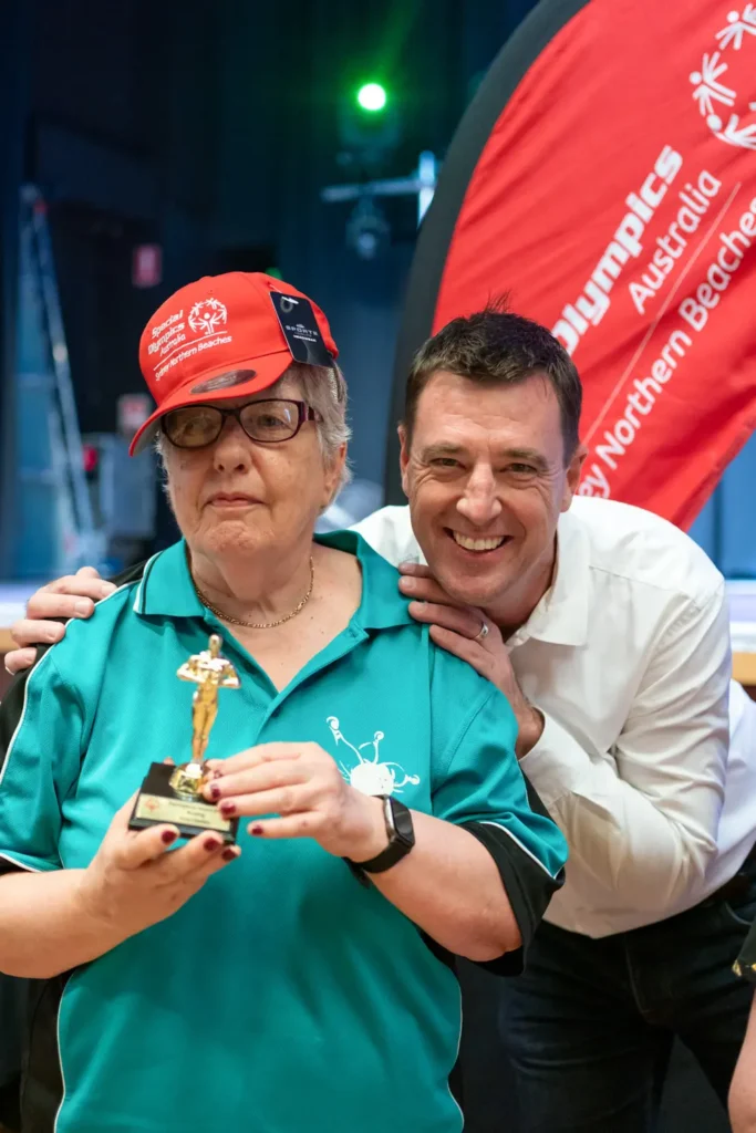 Special Olympics participant holding sports award trophy with Michael Regan ex Mayor of Northern Beaches Council