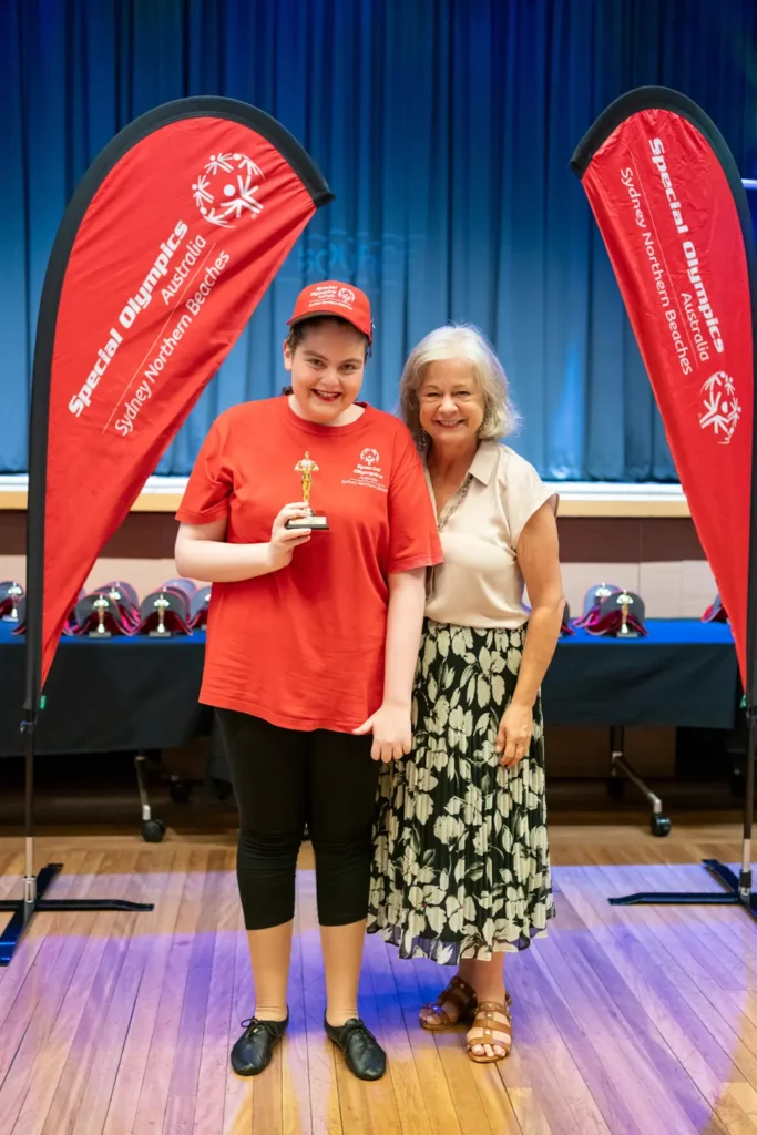 Special Olympics athlete posing with award trophy and Sue Heins Mayor of Northern Beaches Council