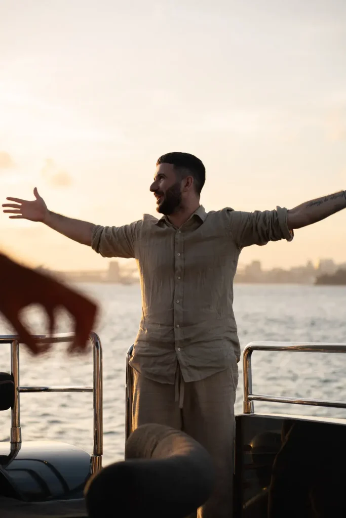 Man with open arms enjoying a sunset yacht party on Sydney Harbour