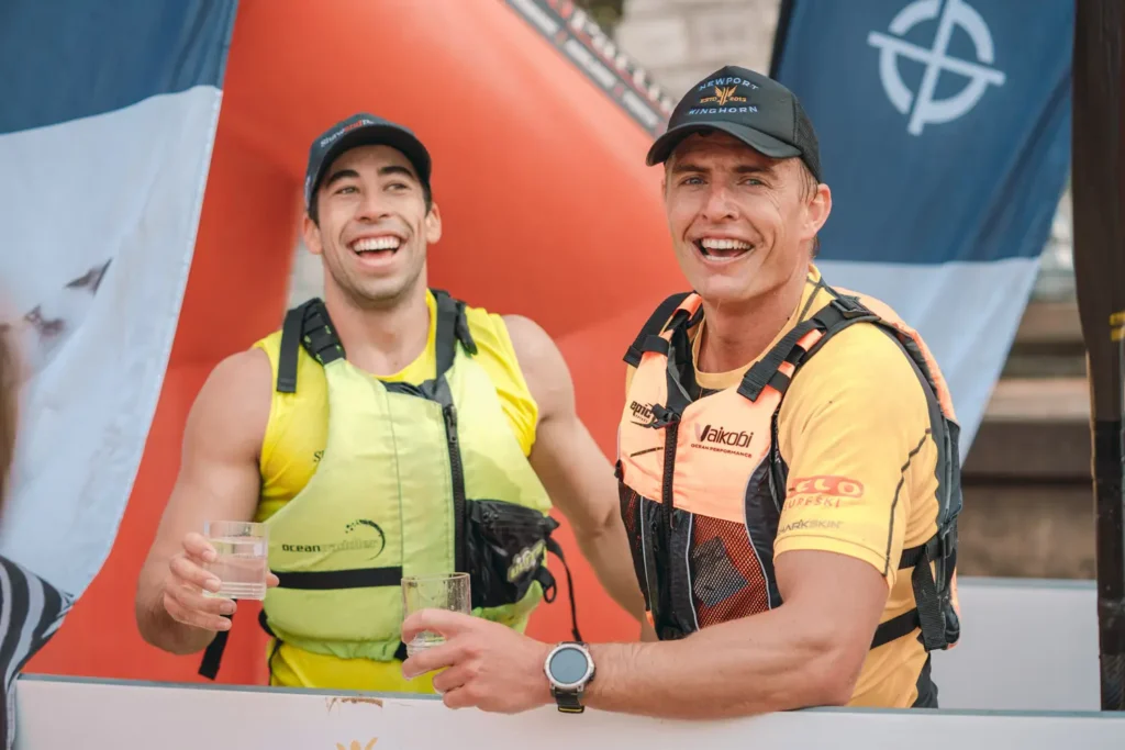 Two smiling surfski competitors celebrating at the finish area after the race