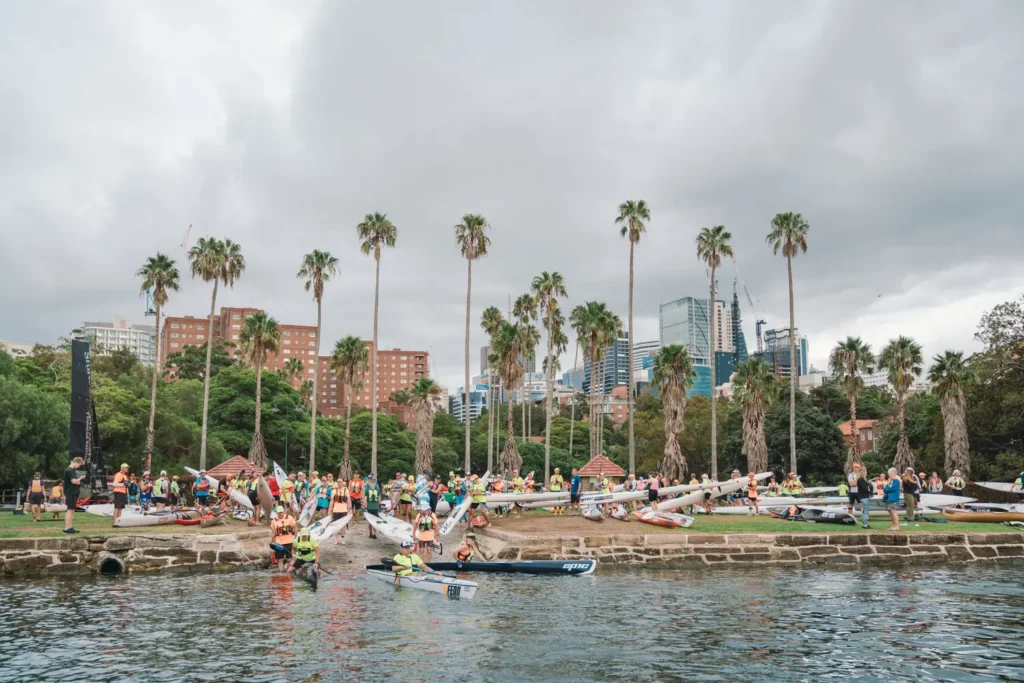 Athletes launching into Sydney Harbour with the Sydney skyline behind them