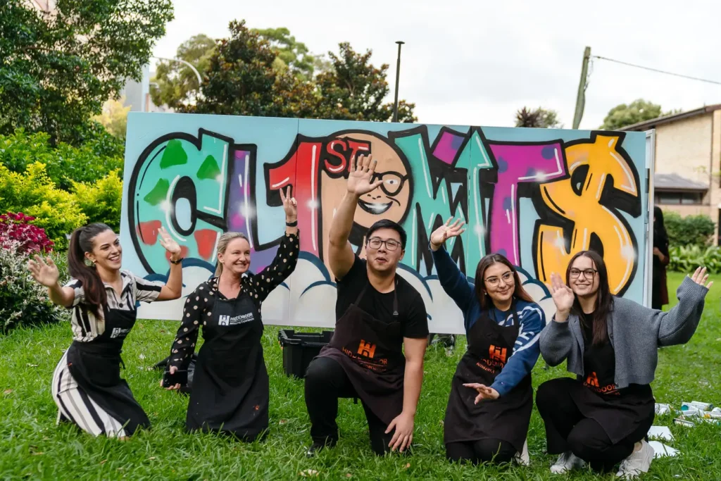 Corporate team posing in front of completed graffiti artwork at a Sydney event