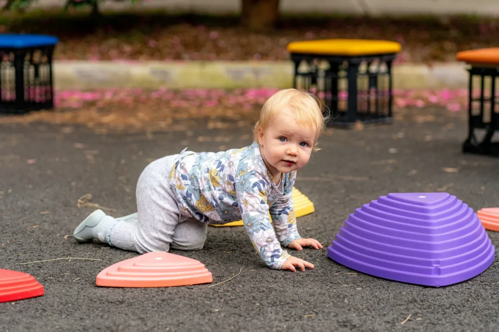 Toddler crawling through colourful play equipment at Wollstonecraft Street Play