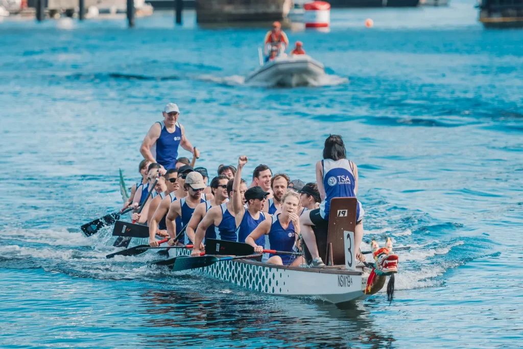 Dragon boat crew celebrating during race on Sydney harbour water