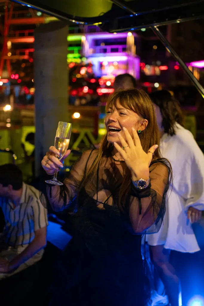 Woman holding a champagne glass while celebrating on a luxury yacht at night