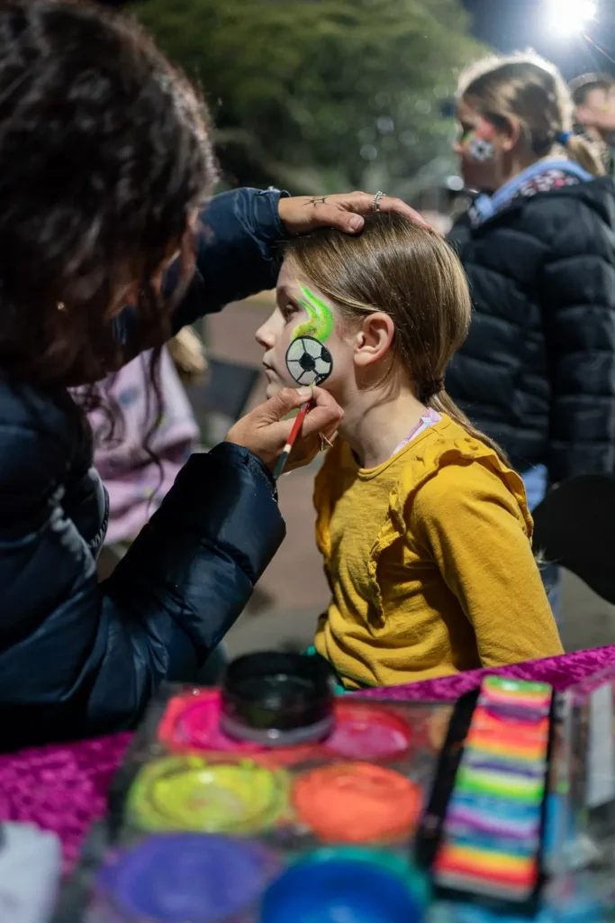 Child having football-themed face paint applied before the Matildas match screening