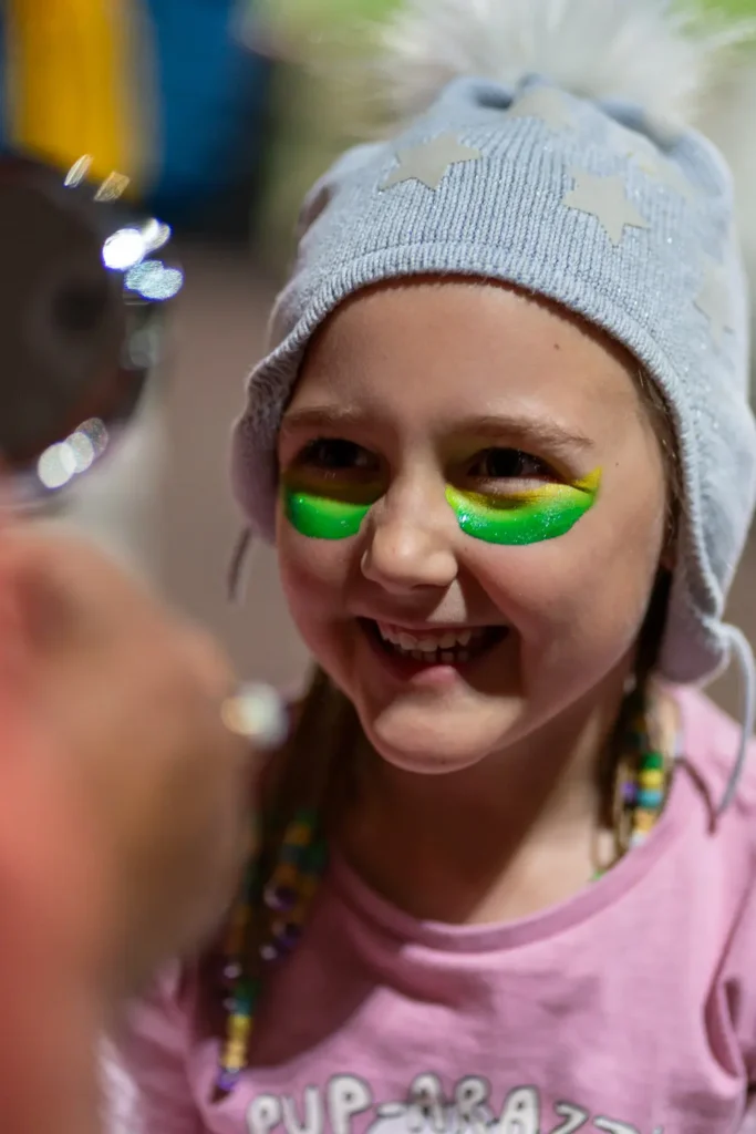 Child having Australian-themed face paint applied before the Matildas live site at North Sydney Oval