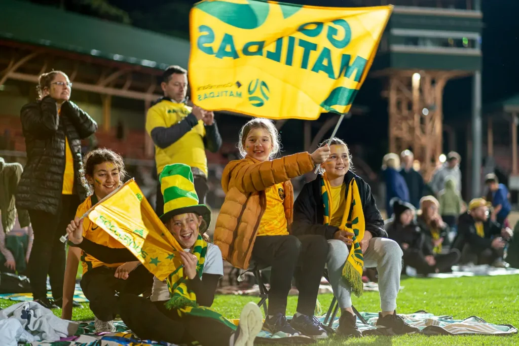Young Matildas fans waving Australian flags during the live screening