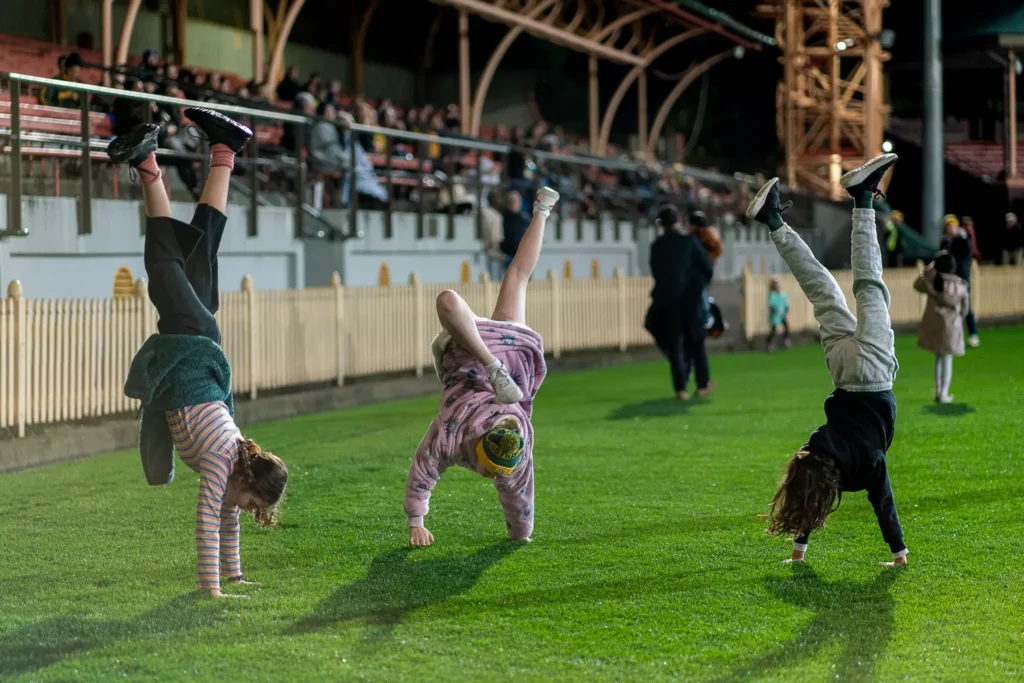 Children doing cartwheels on the grass during the Matildas live site at North Sydney Oval