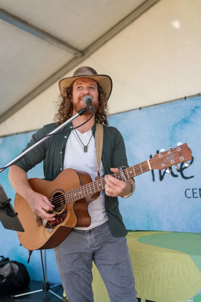 Acoustic guitarist singing on stage at an outdoor community festival