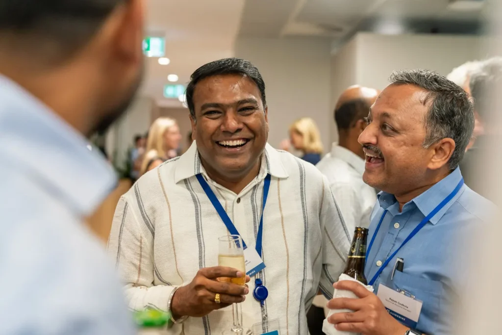 Colleagues laughing together over drinks at a relaxed corporate event